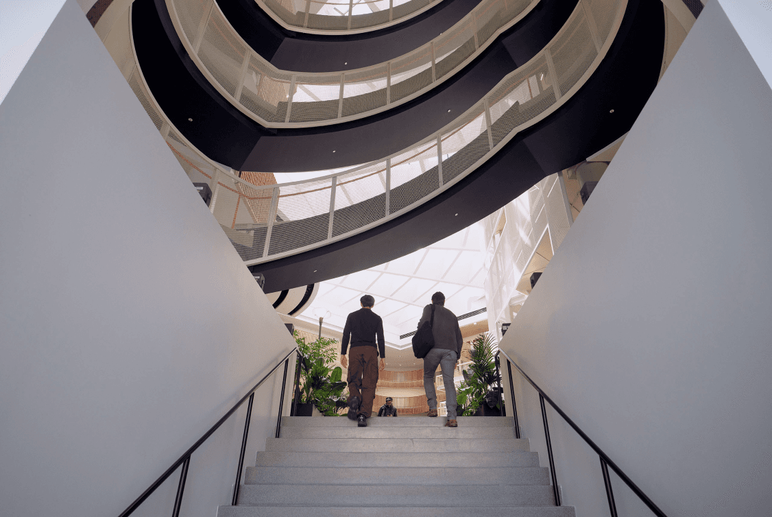 Two people walking up a staircase into the Scale HQ atrium.
